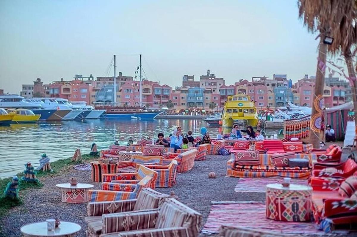 uma marina com mesas, cadeiras e barcos na água