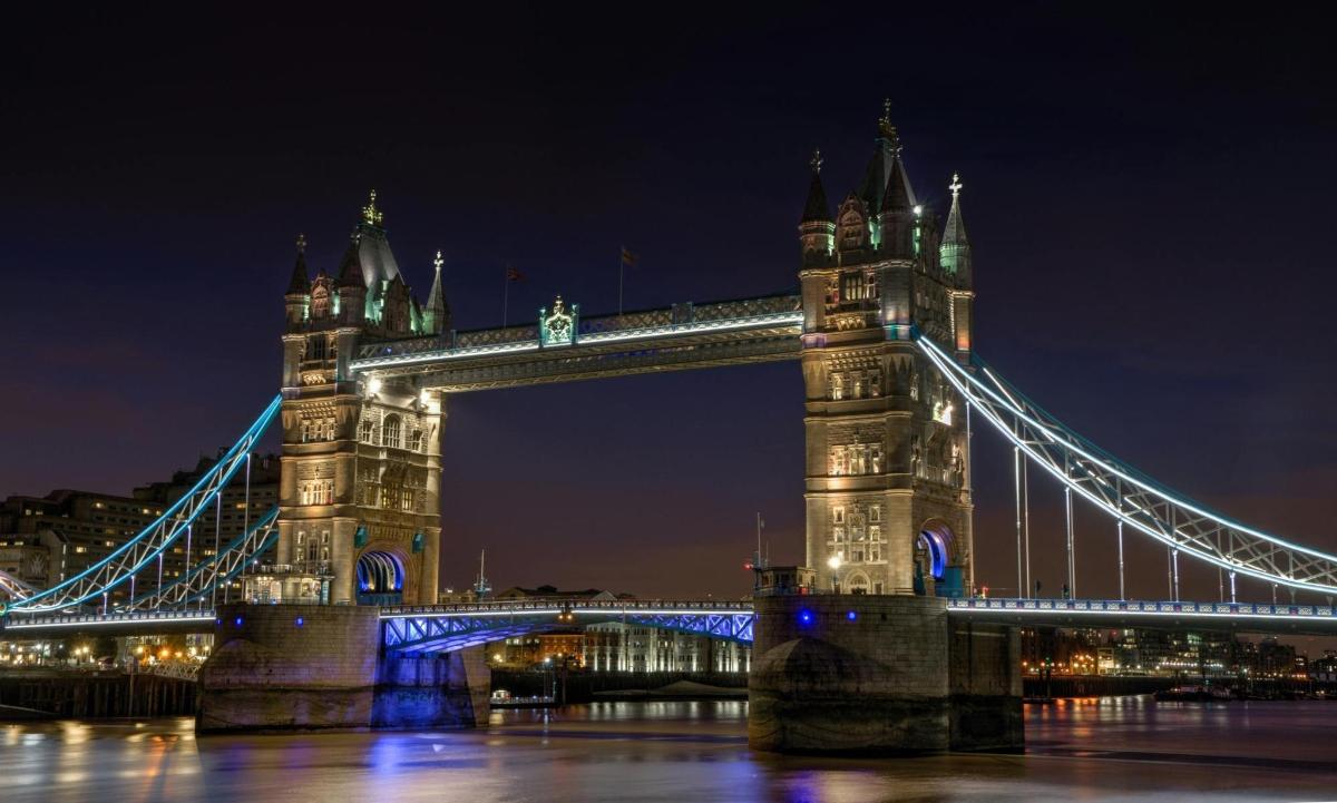 a suspension bridge over the water at night