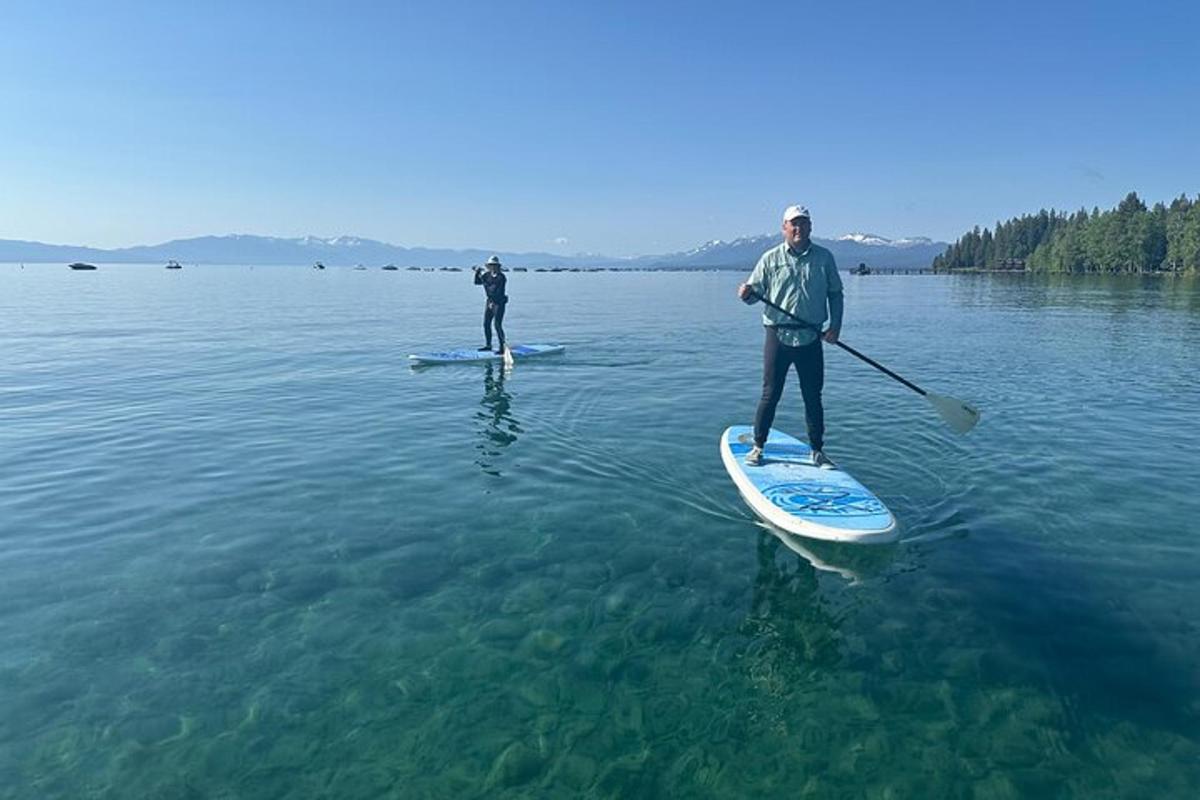 dues persones estan dretes sobre taules de paddle surf a l'aigua