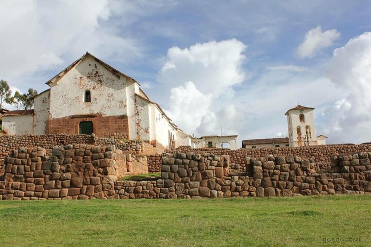 Un edificio detrás de un muro de piedra con una iglesia detrás.