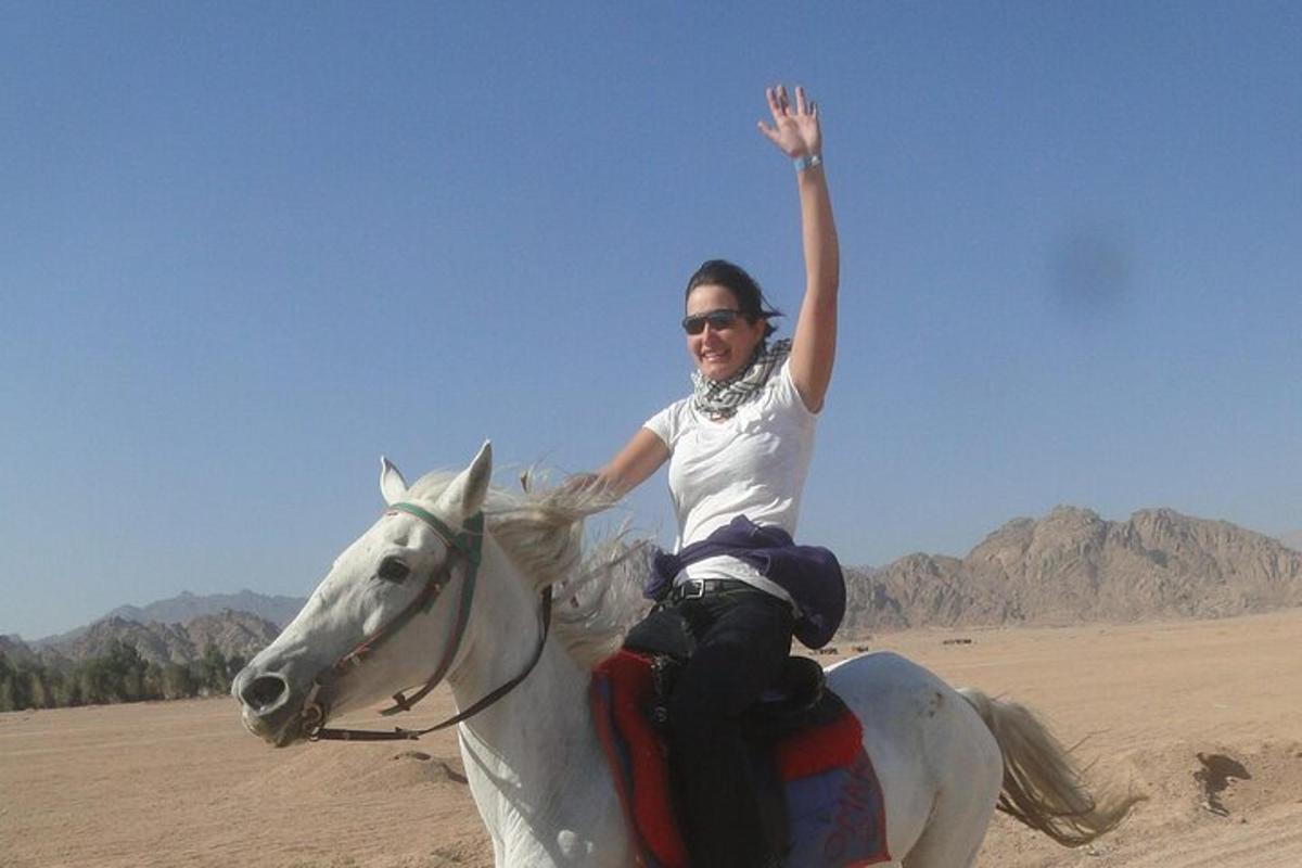 a woman riding a white horse in the desert