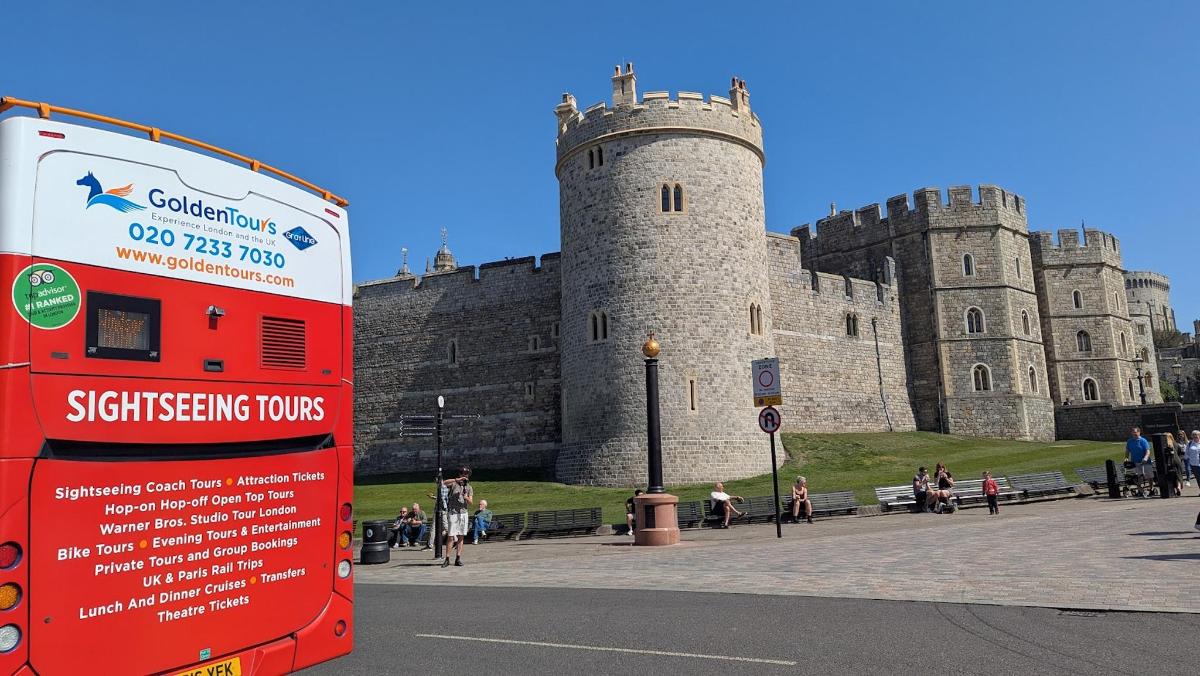 un bus rouge à impériale garé devant un château