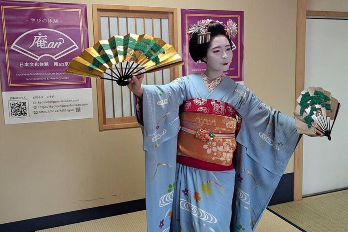 a woman dressed in a kimono holding a fan