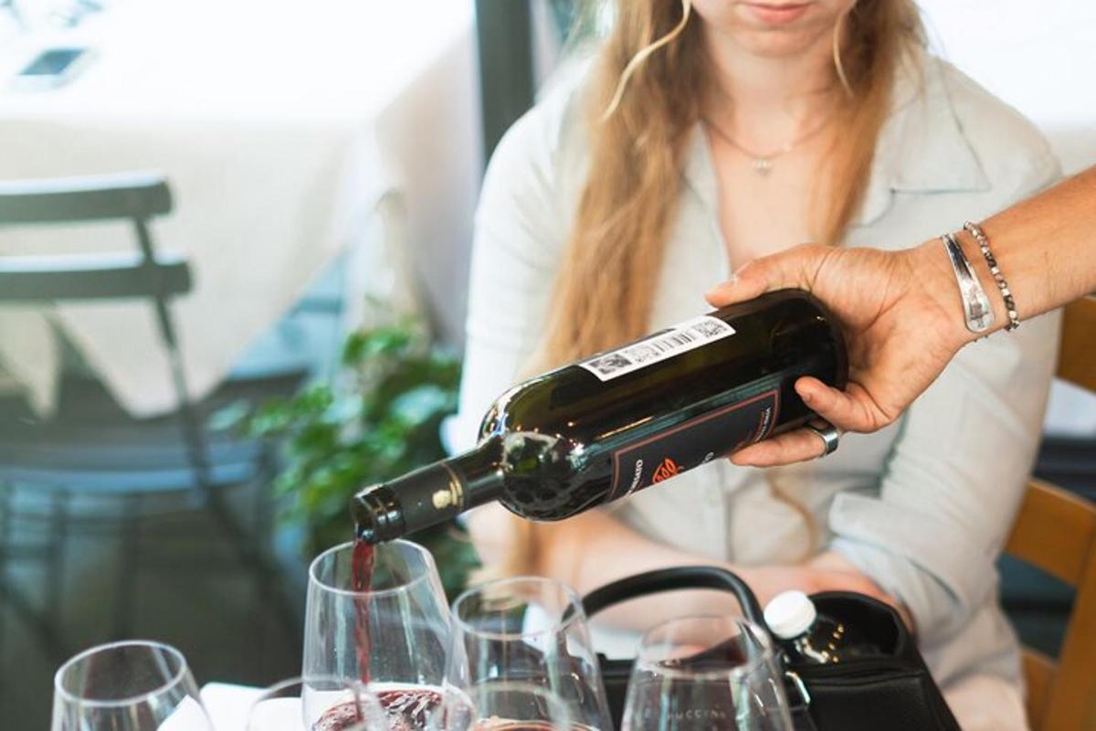 a woman pouring a bottle of wine into glasses