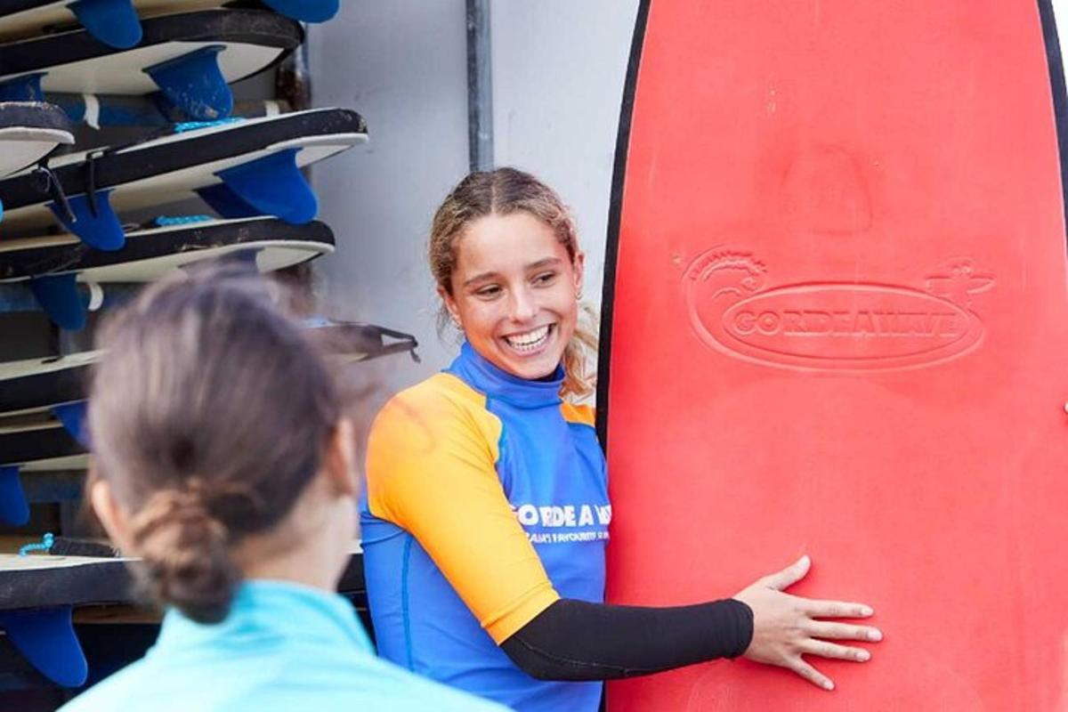 a woman is standing next to a red surfboard