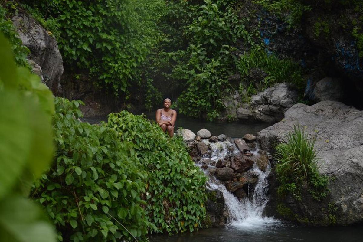 Un hombre parado en un río con una cascada.