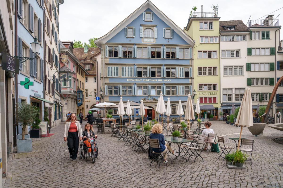 a group of people walking down a street with buildings