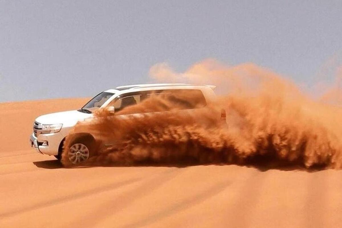 bílý kamion jedoucí pískem v poušti