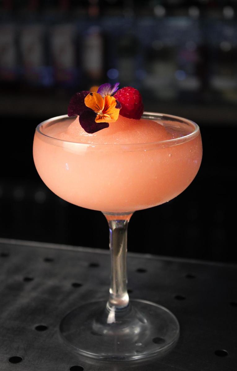 马提尼酒杯中的粉色饮料，配覆盆子