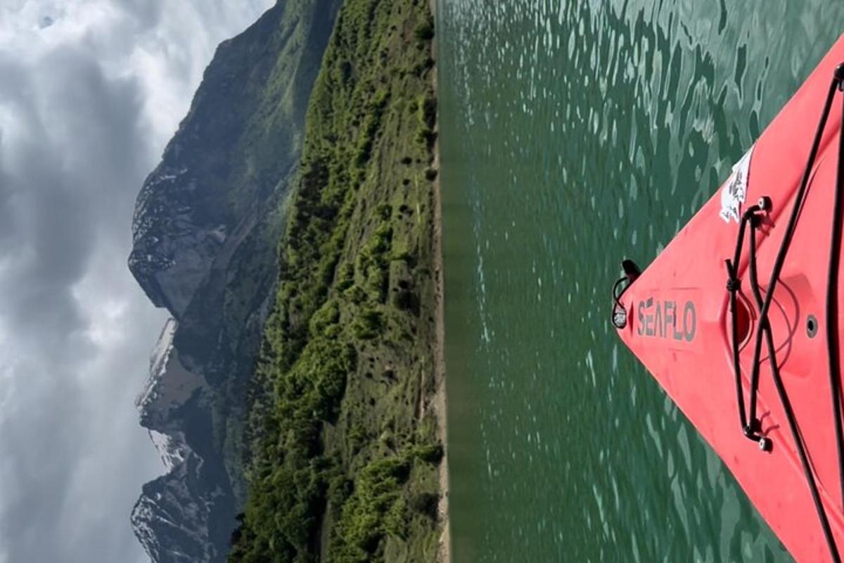 a red umbrella flying over the water next to a mountain