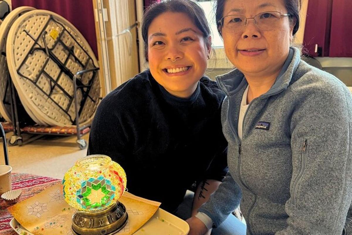 two women standing next to a table with a glass jar