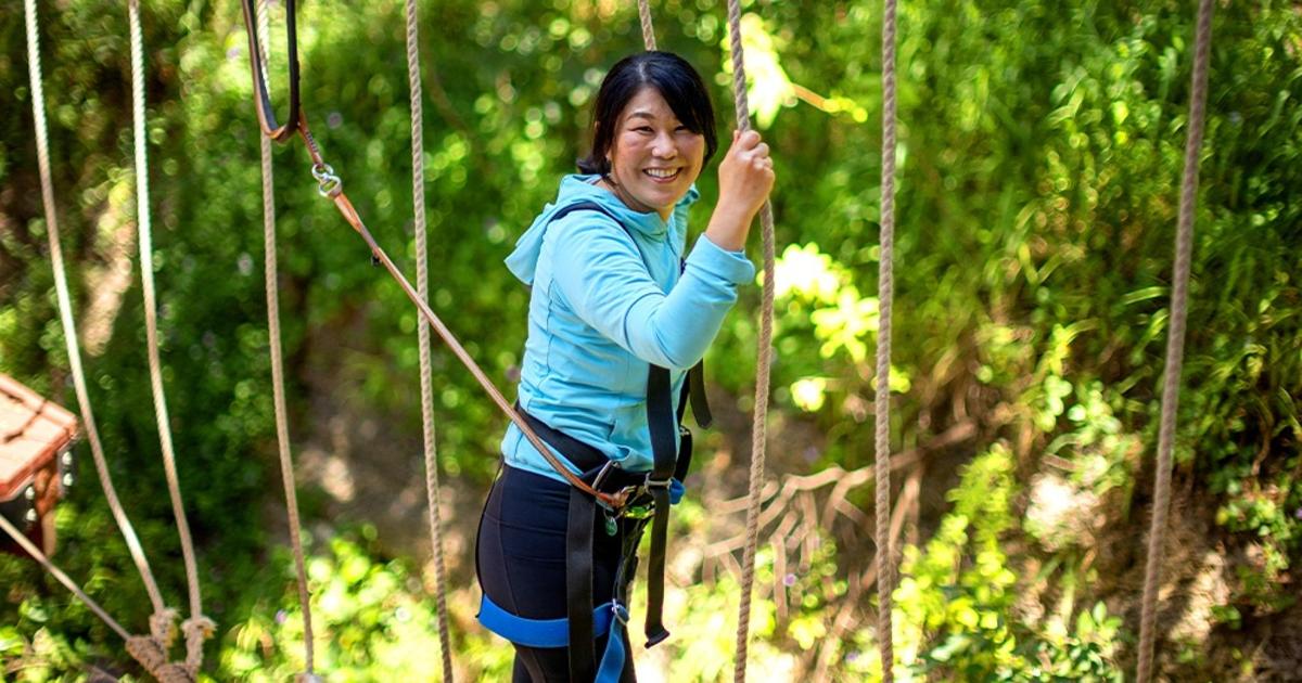 a woman on a zip line in the forest