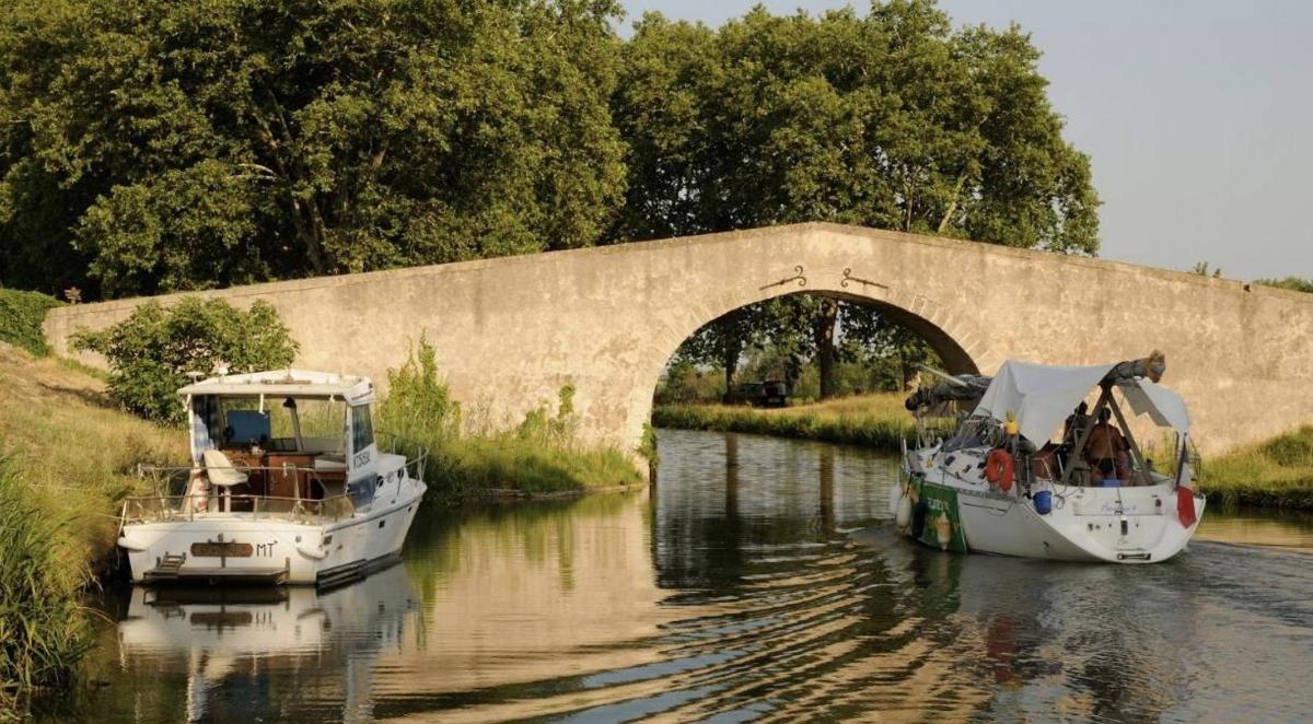 two boats in the water under a bridge
