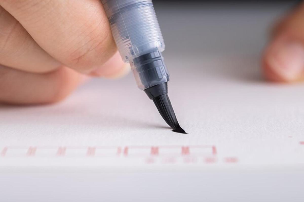 a person writing on a piece of paper with a pen