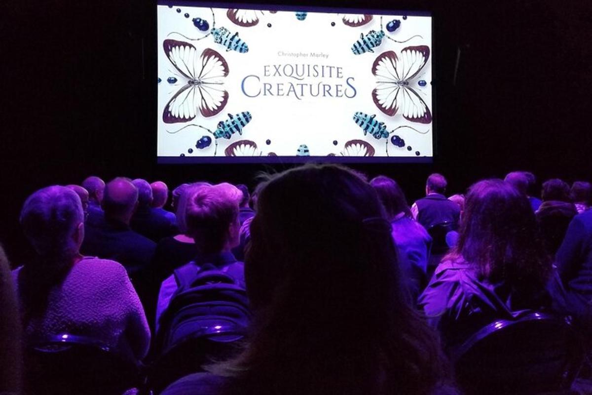 a crowd of people sitting in a theater watching a presentation