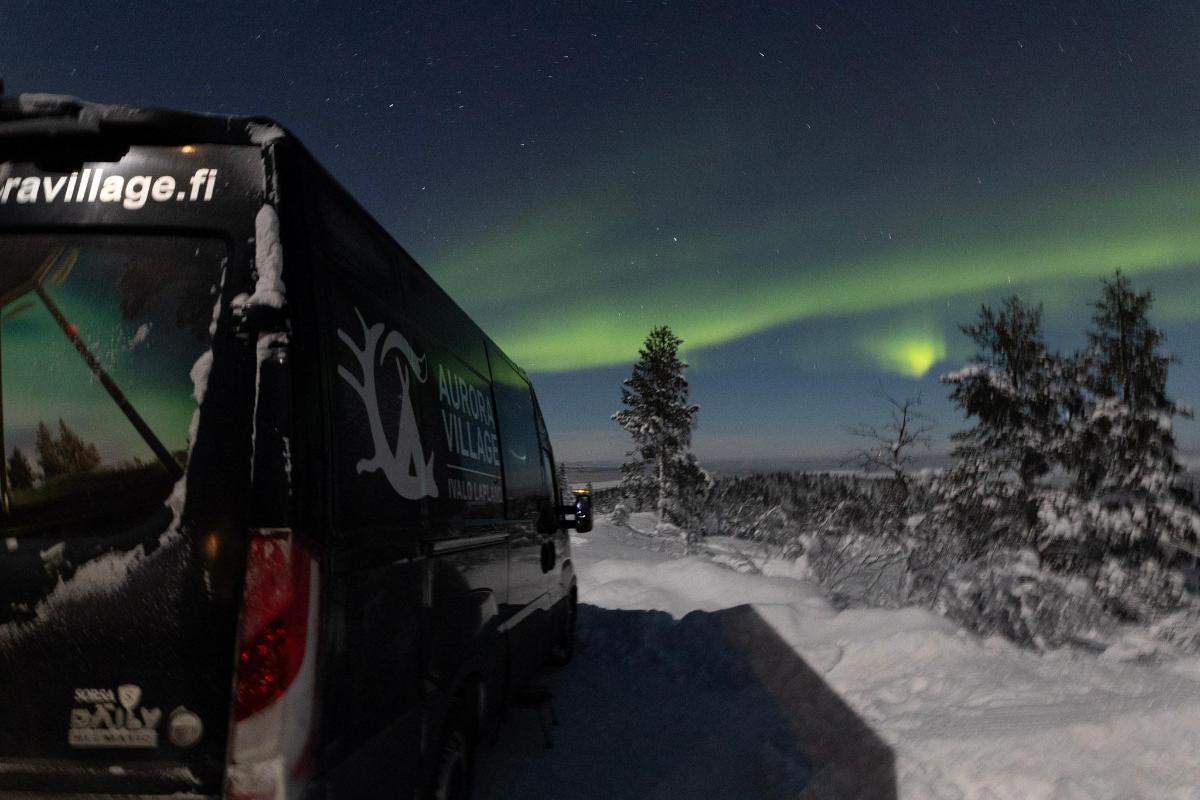 a bus is parked in the snow under the aurora