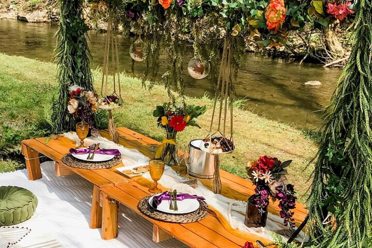 a wooden picnic table with plates and flowers on it