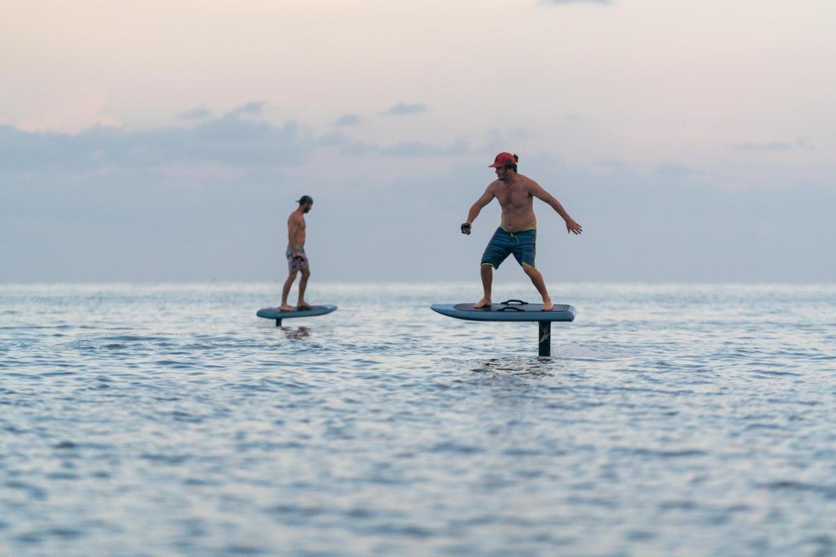 Двоє чоловіків стоять на дошках для серфінгу у воді