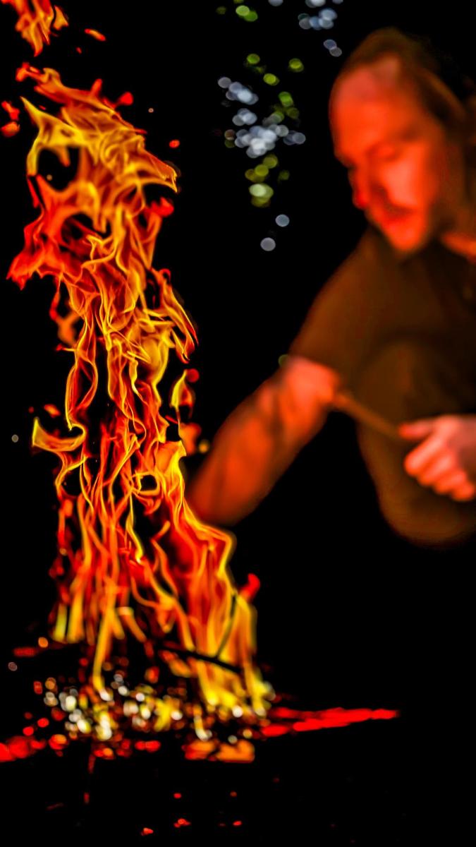 a man standing next to a fire with a spoon