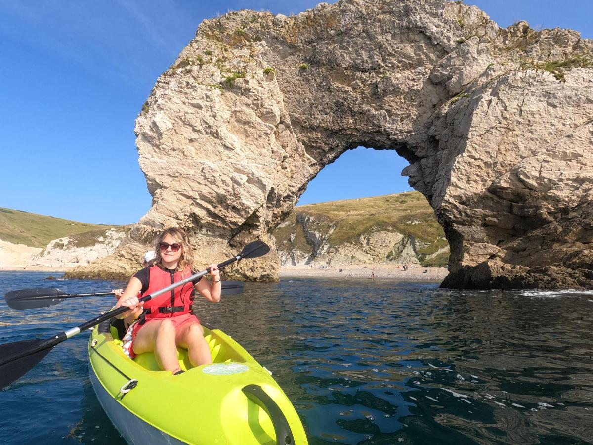 a woman in a kayak in front of an arch in the water