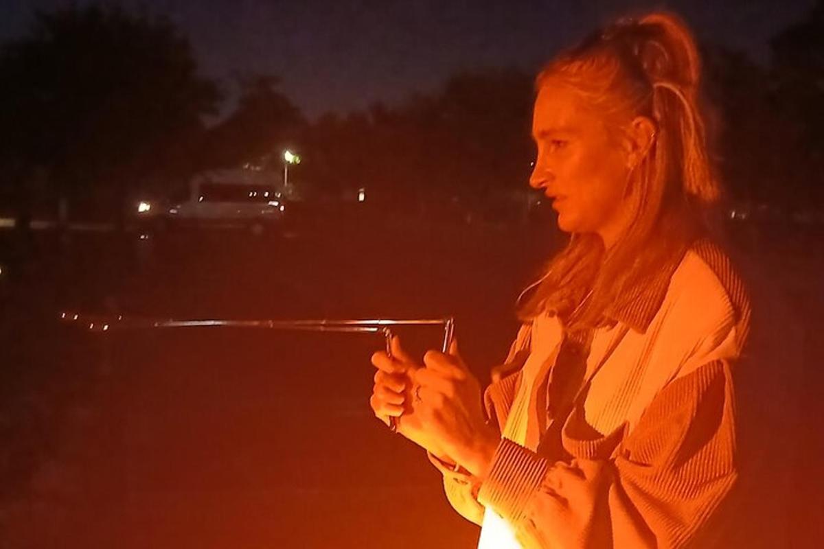 a woman is holding a gun at night