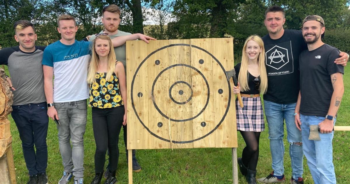 eine Gruppe von Menschen steht neben einem Holzschild