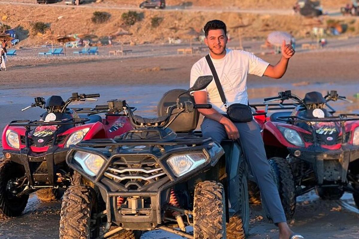 muž sedící na čtyřkolce na pláži