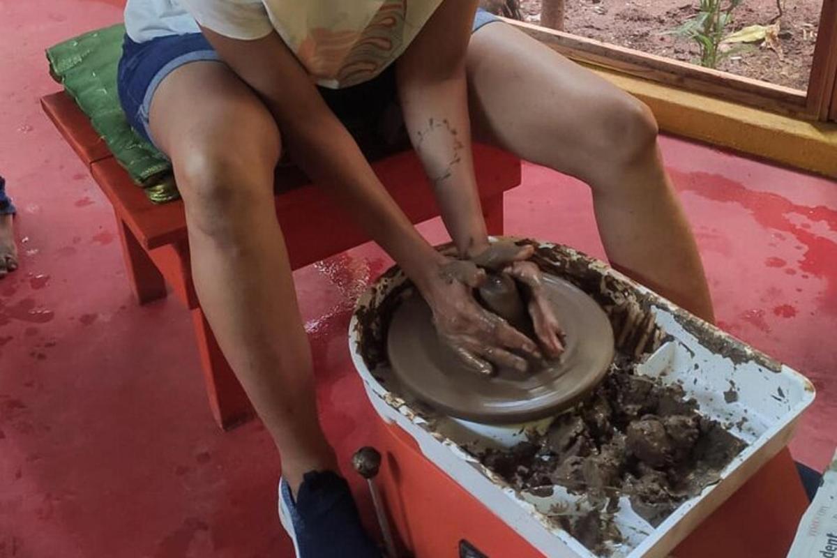 a person sitting on a table making a clay wheel