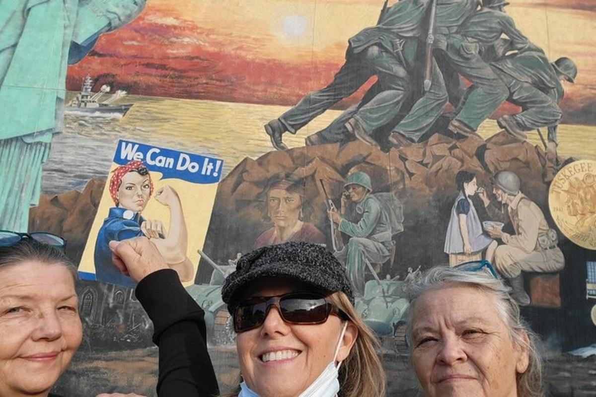 three women are standing in front of a mural