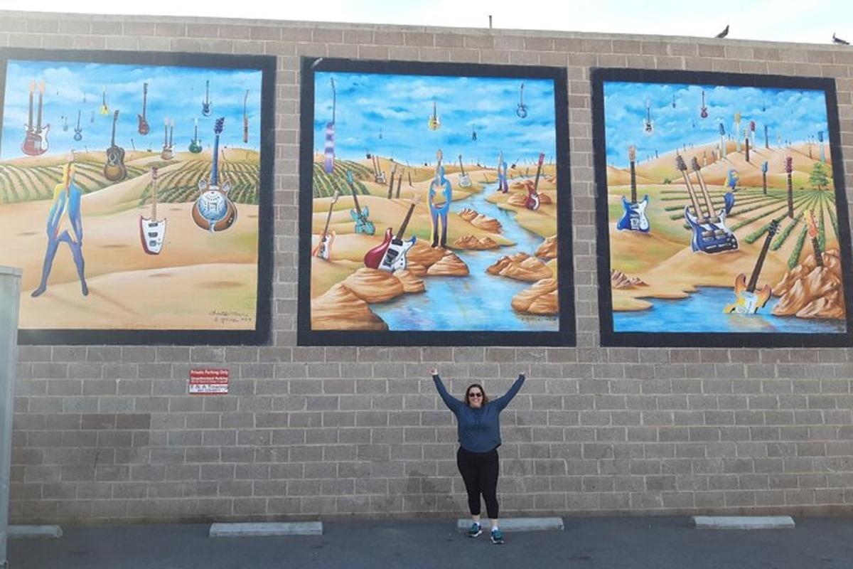 a woman standing in front of a mural with her arms up