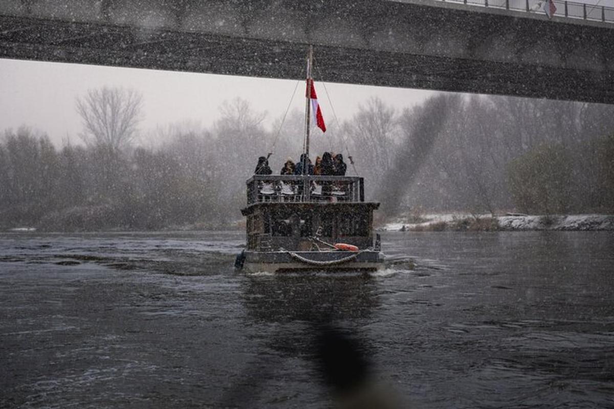 a group of people on a boat in the water under a bridge