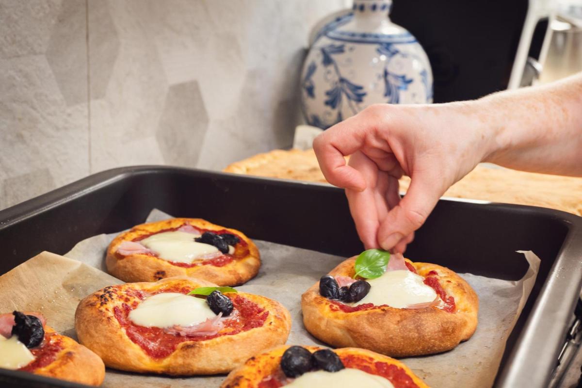 一个人正伸手去拿小披萨上的一片绿叶。