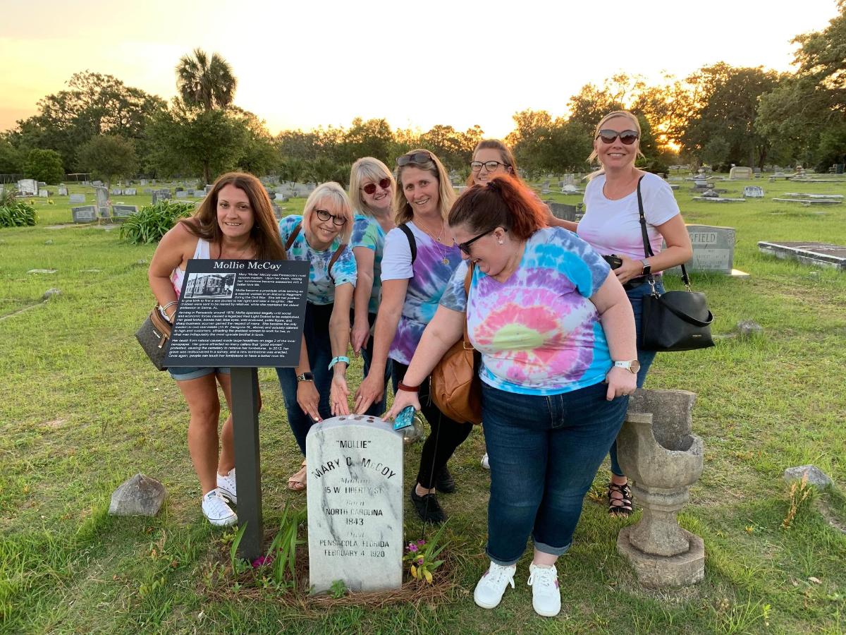 a group of women standing around a sign in a cemetery