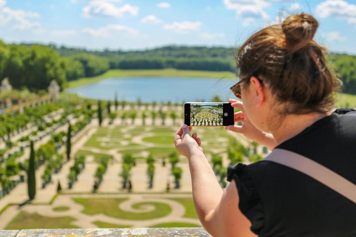 a woman taking a picture of a garden with her cell phone