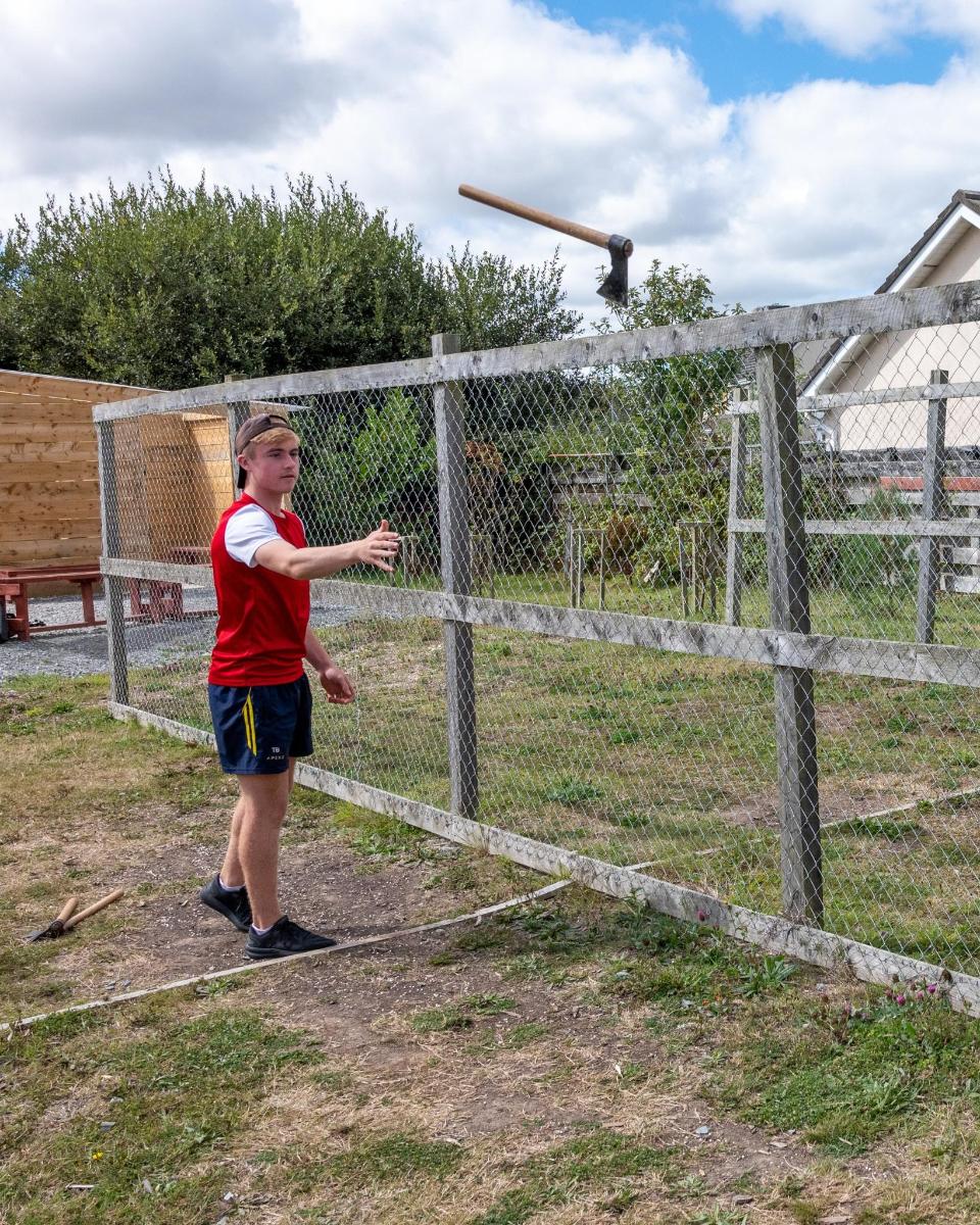 a boy is standing next to a fence
