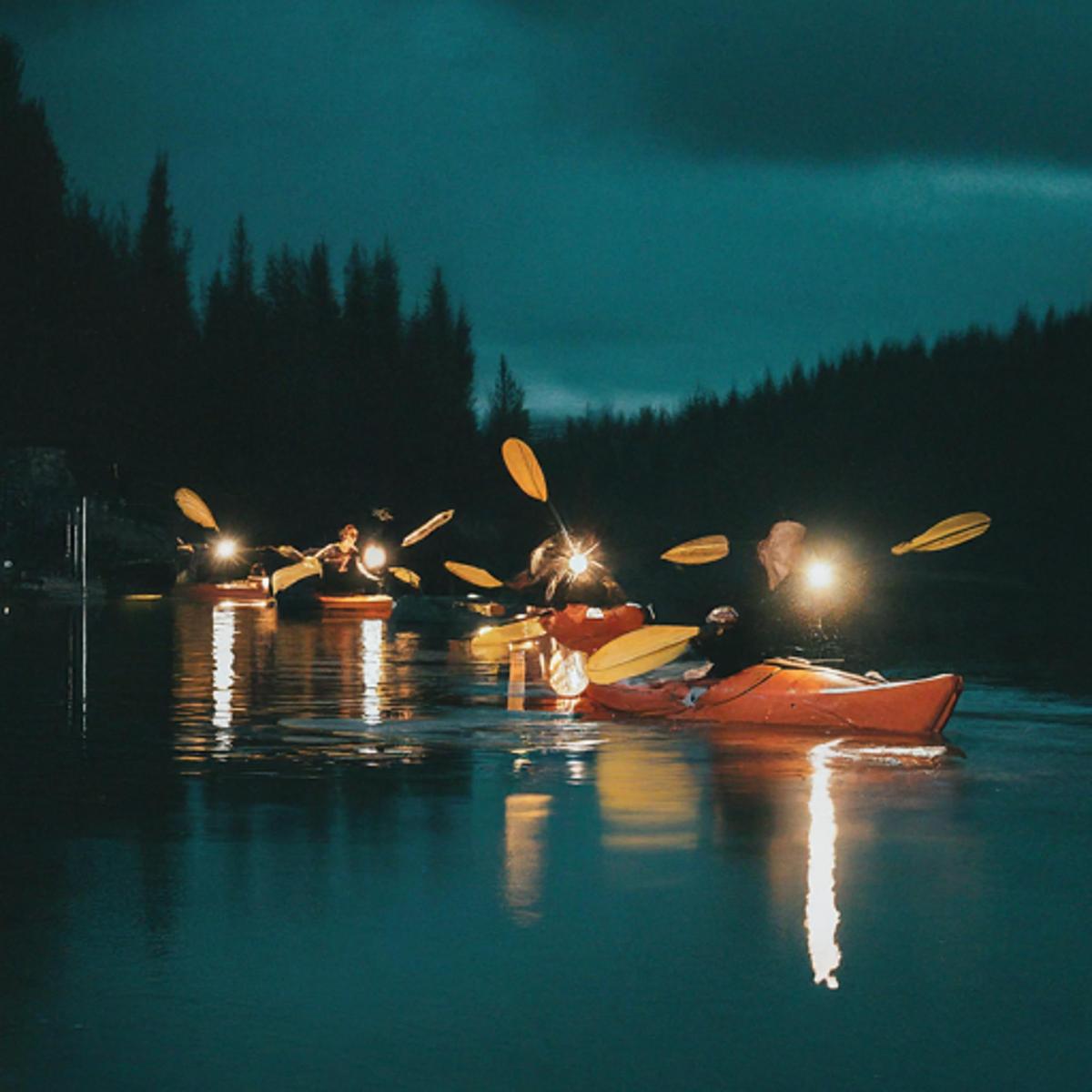 a group of people in kayaks on the water at night