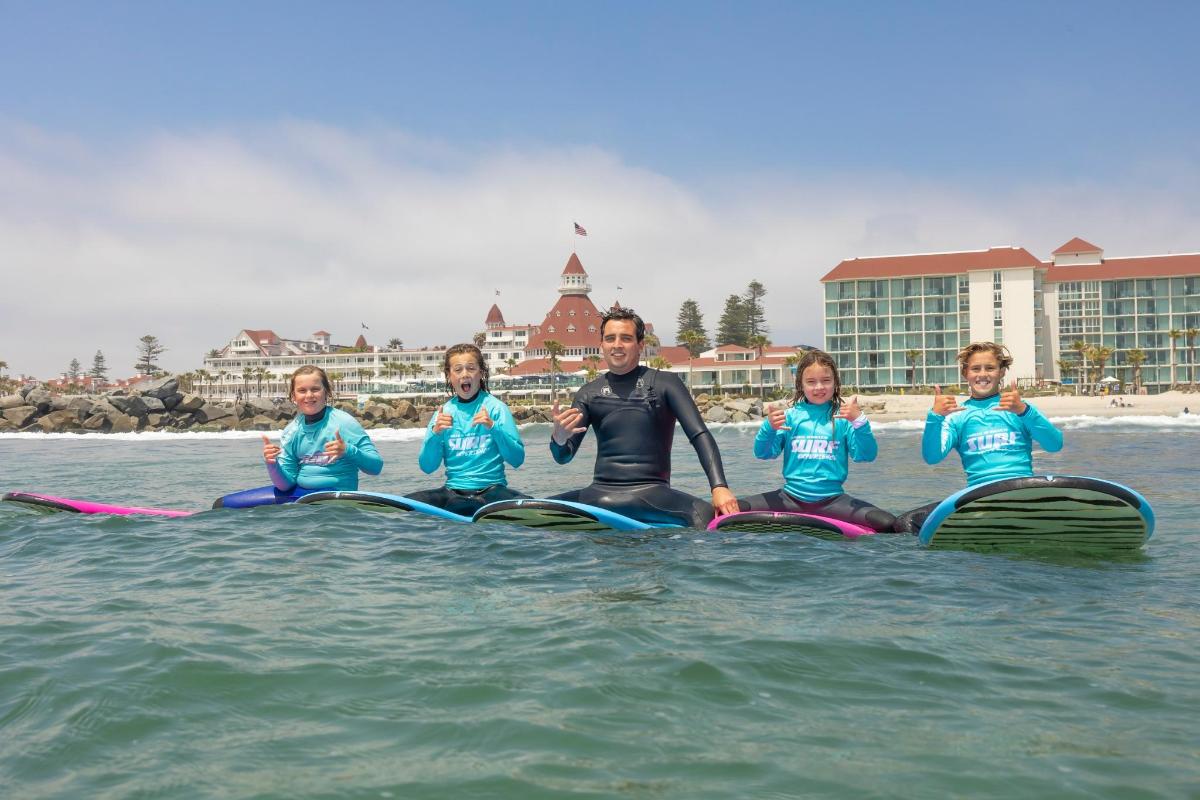 a man and three children sitting on surfboards in the water
