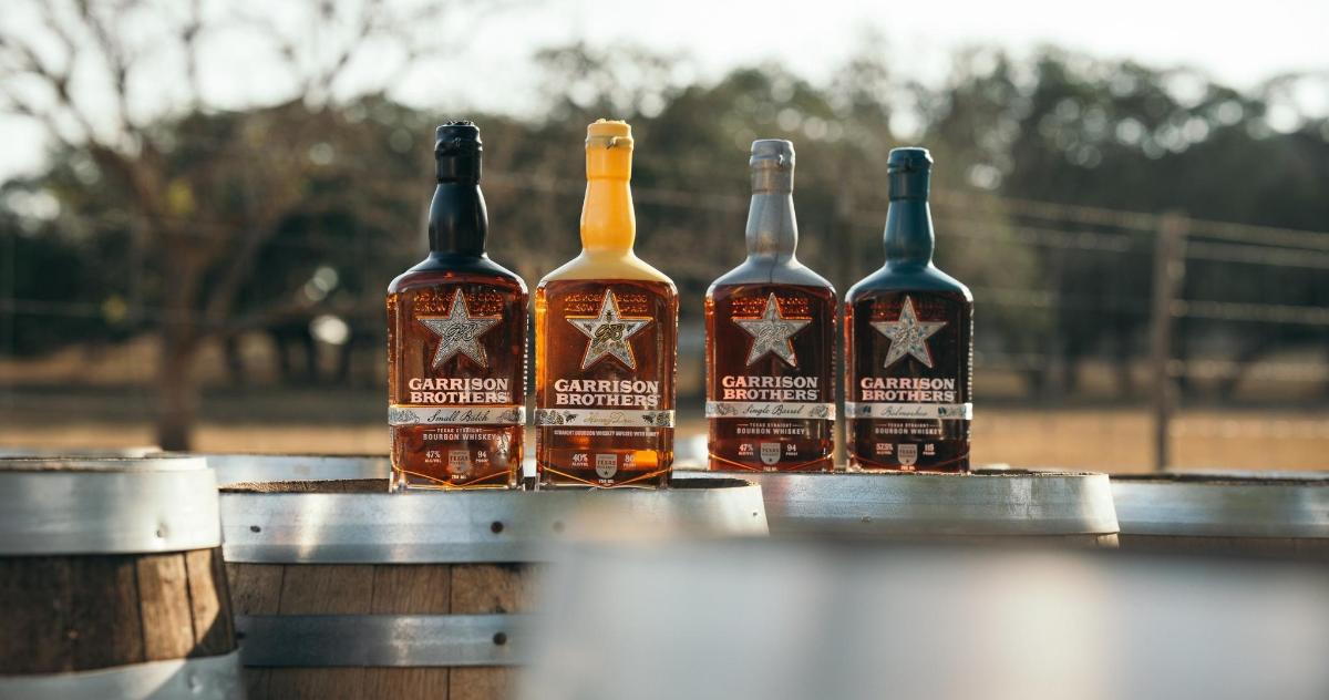 a group of four bottles of whiskey sitting on a rail