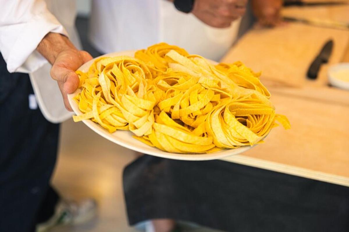 a person is holding a plate of pasta