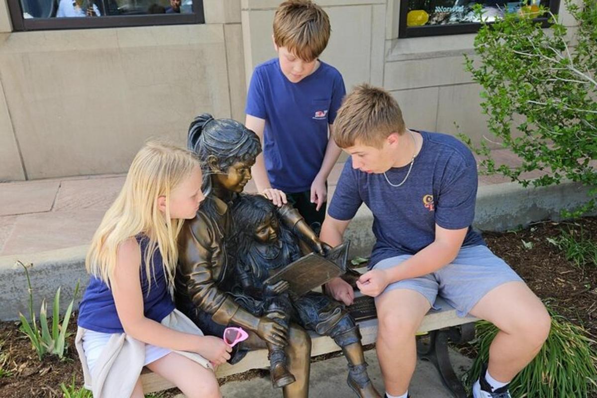 a group of children standing around a bronze statue