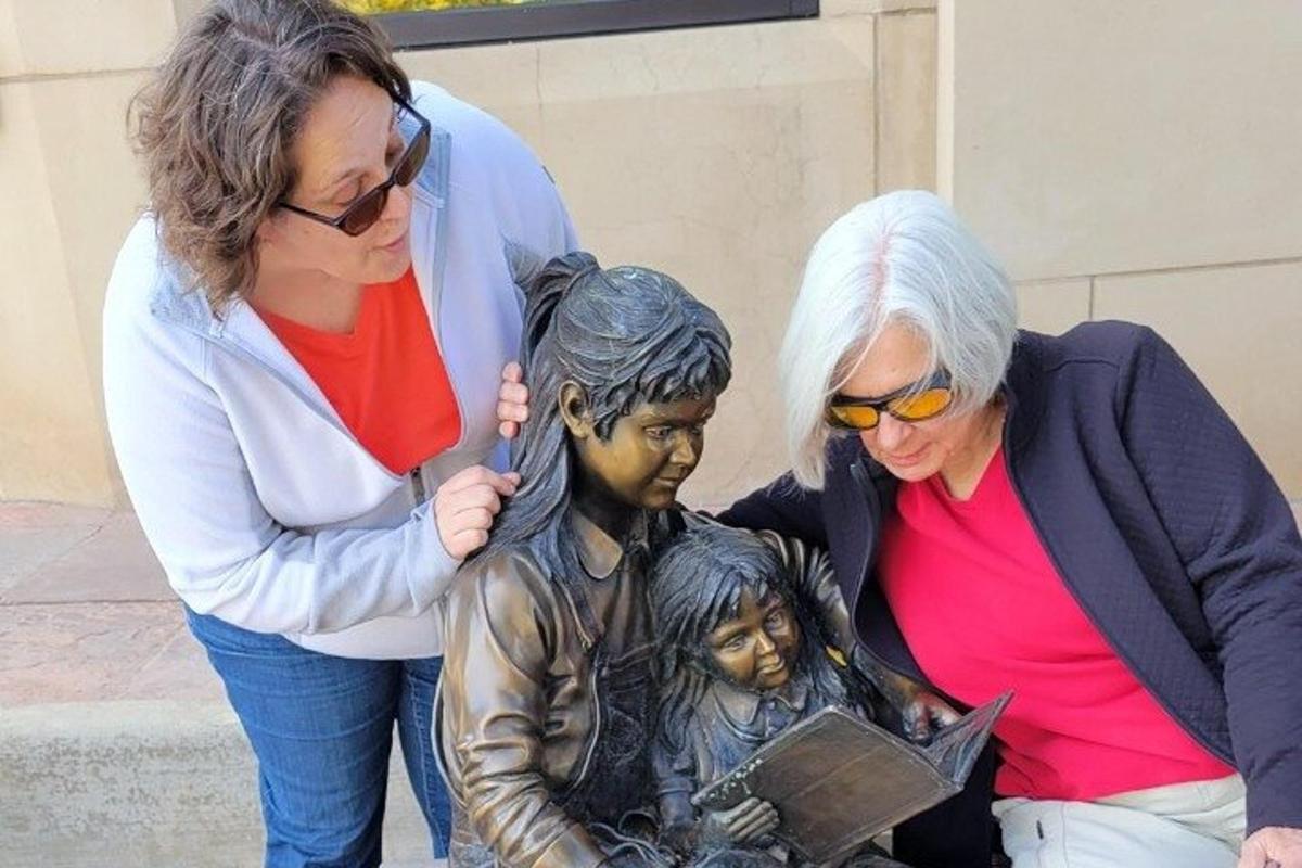 two women looking at a statue of a boy