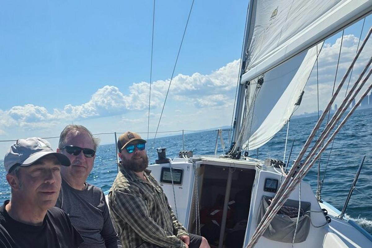 three men standing on a sail boat in the water