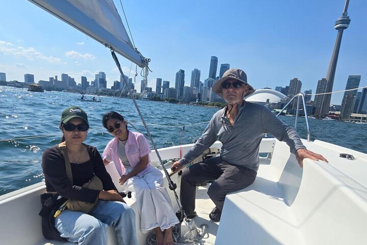 three people sitting on a sail boat in the water