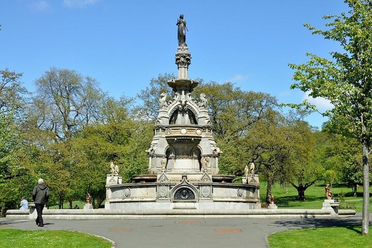 a man walking past a fountain in a park
