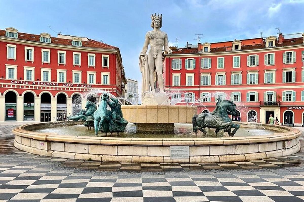 a fountain in a square with a statue in front of buildings