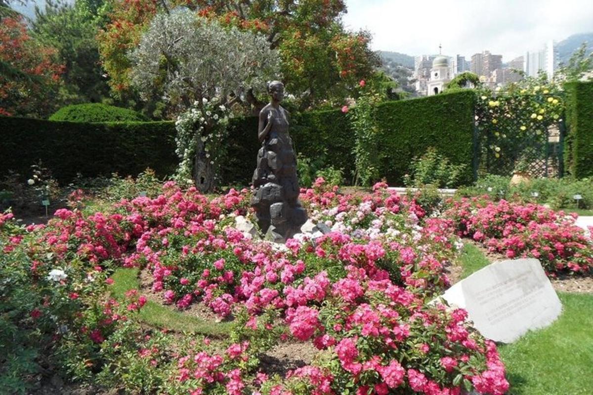 a statue in a garden with pink flowers