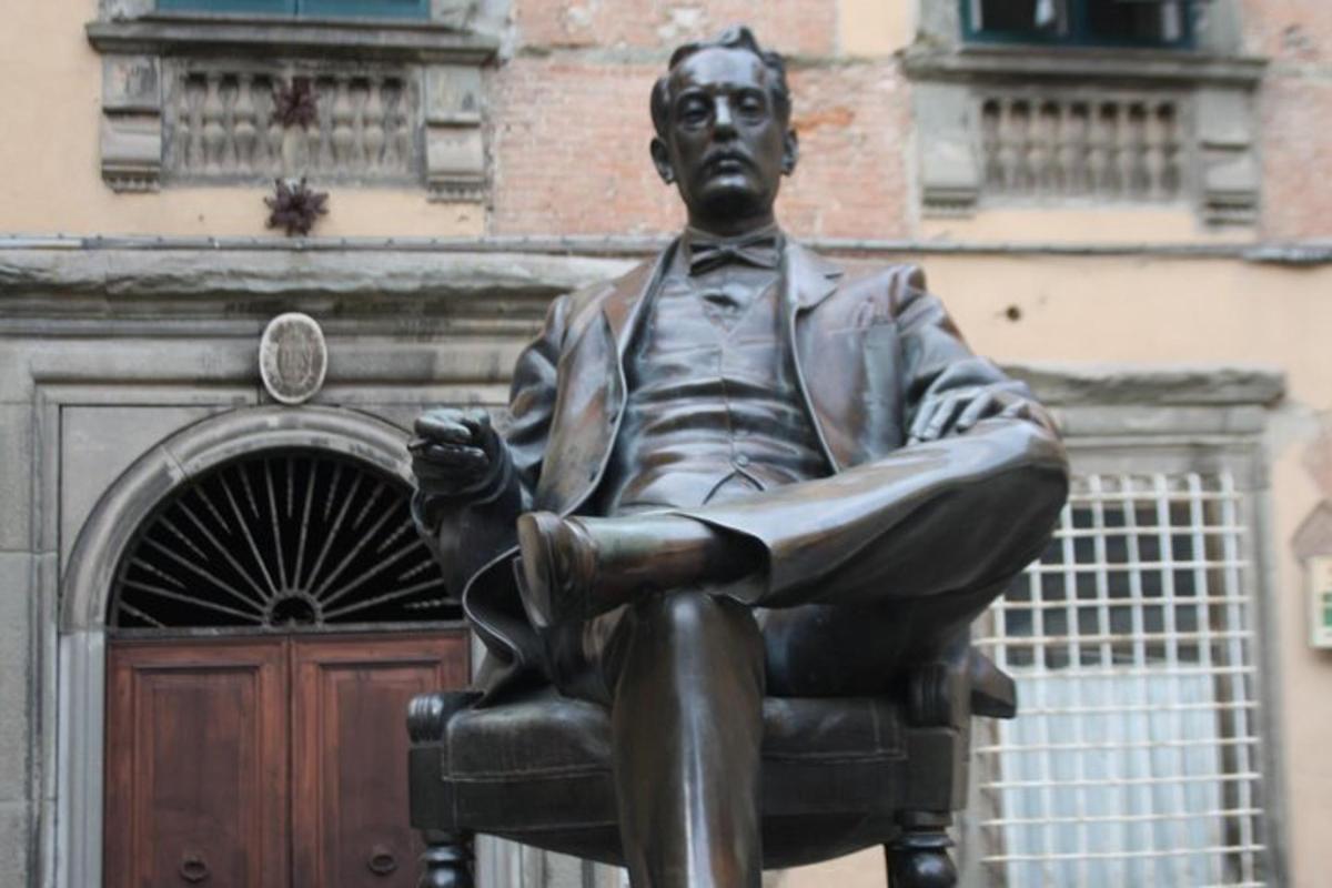 a statue of a man sitting in a chair in front of a building