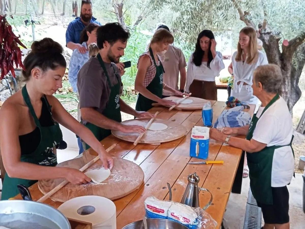 a group of people standing around a table making pizzas
