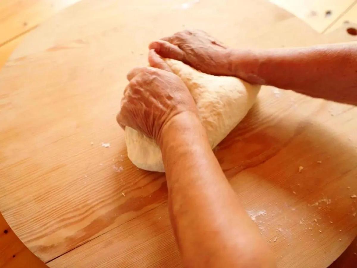 a person kneading the dough on a wooden table