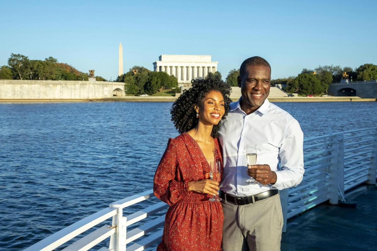 a man and a woman standing on a pier next to the water